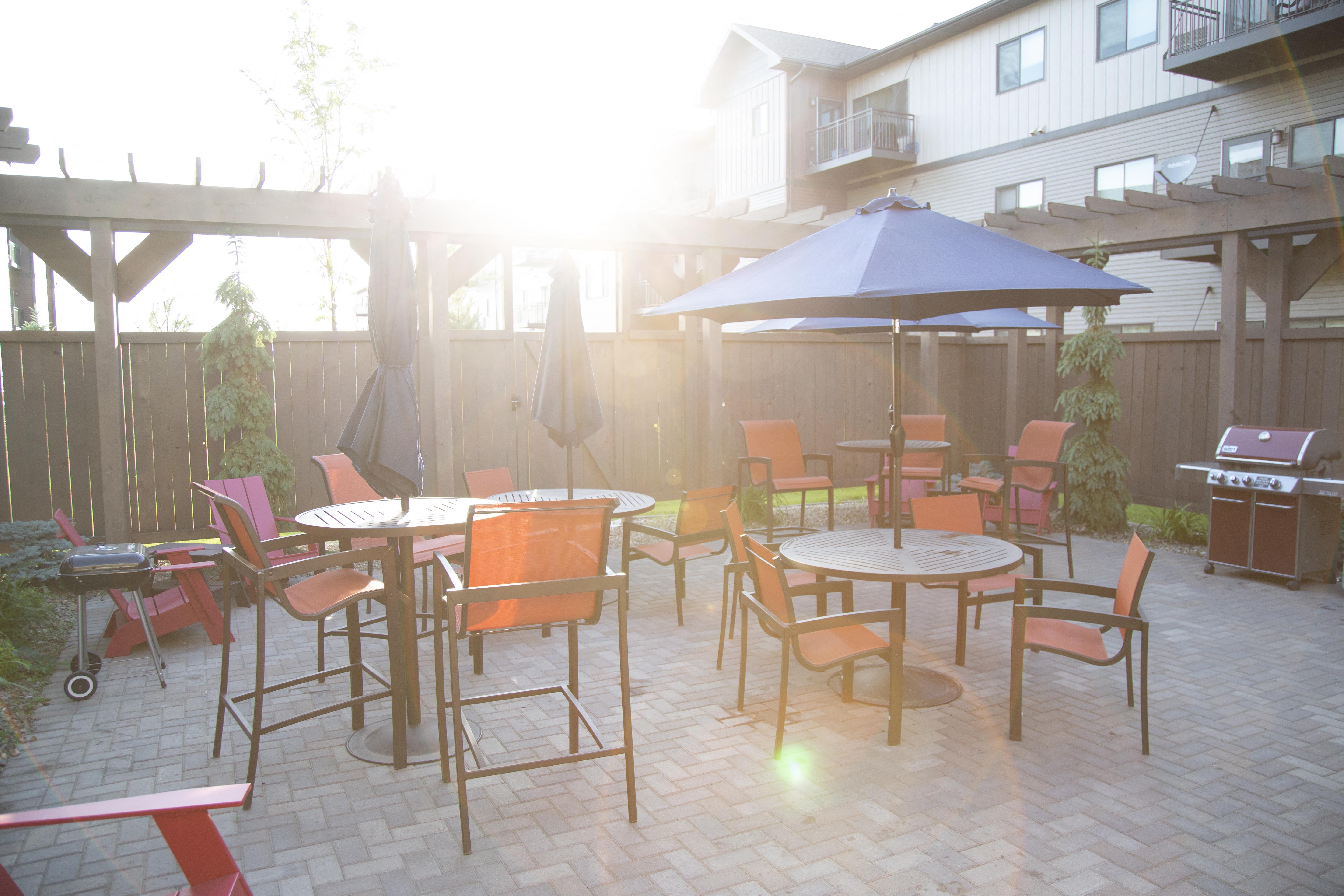 Outdoor community patio with a variety of tables and seating. There are multiple pergolas covering the grilling areas.